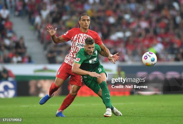 Kiliann Sildillia of Sport-Club Freiburg clashes with Ermedin Demirovic of FC Augsburg during the Bundesliga match between Sport-Club Freiburg and FC...