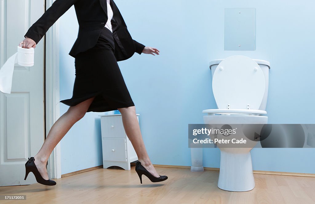 Female executive running to the toilet
