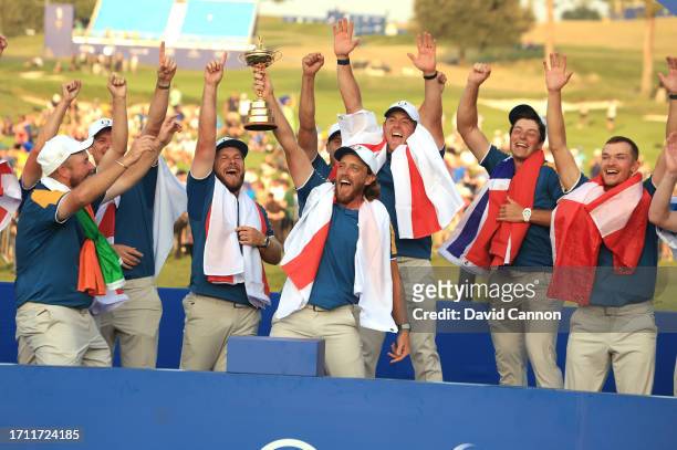 Tommy Fleetwood of England and The European Team raises the Ryder Cup beside Tyrrell Hatton and Rory McIlroy at the official presentation after the...