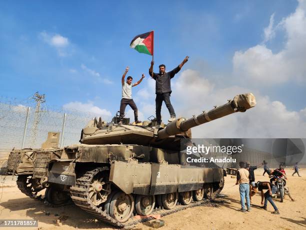 Hamas' armed wing, the Izz ad-Din al-Qassam Brigades hold a Palestinian flag as they destroy a tank of Israeli forces in Gaza City, Gaza on October...