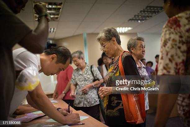 People queue up to receive free N95 masks at the Ang Mo Kio Community Center on June 23, 2013 in Singapore. Elderly and low income Singaporeans were...