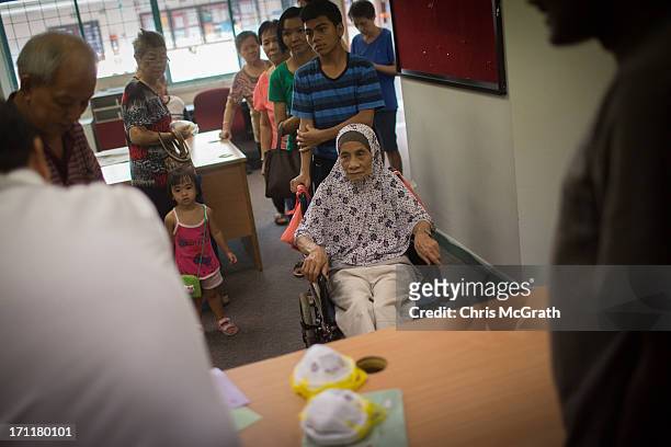 Woman in a wheelchair queues up to receive free N95 masks at the Ang Mo Kio Community Center on June 23, 2013 in Singapore. Elderly and low income...