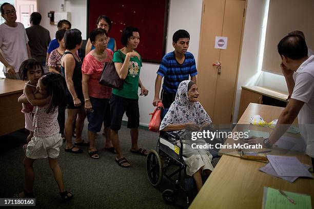 Woman in a wheelchair queues up to receive free N95 masks at the Ang Mo Kio Community Center on June 23, 2013 in Singapore. Elderly and low income...