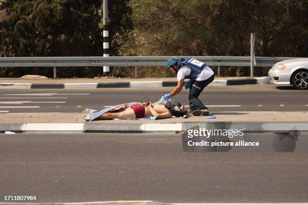 October 2023, Israel, Tel Aviv: An Israeli paramedic covers the body of a dead Palestinian man. Palestinian militants in Gaza unexpectedly fired...