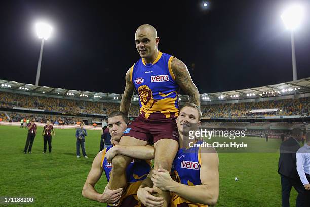 Ashley McGrath of the Lions is chaired off by team mates Tom Rockcliff and Jack Redden after his 200th game during the round 13 AFL match between the...