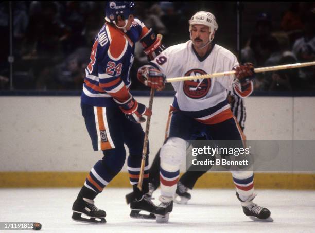 Bryan Trottier of the New York Islanders checks Kevin McClelland of the Edmonton Oilers during the 1984 Stanley Cup Finals in May, 1984 at the Nassau...