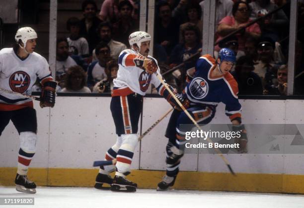 Bryan Trottier of the New York Islanders checks Kevin Lowe of the Edmonton Oilers during the 1984 Stanley Cup Finals in May, 1984 at the Nassau...