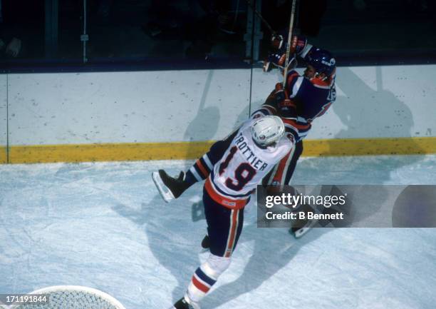 Bryan Trottier of the New York Islanders checks Willy Lindstrom of the Edmonton Oilers during the 1984 Stanley Cup Finals in May, 1984 at the Nassau...