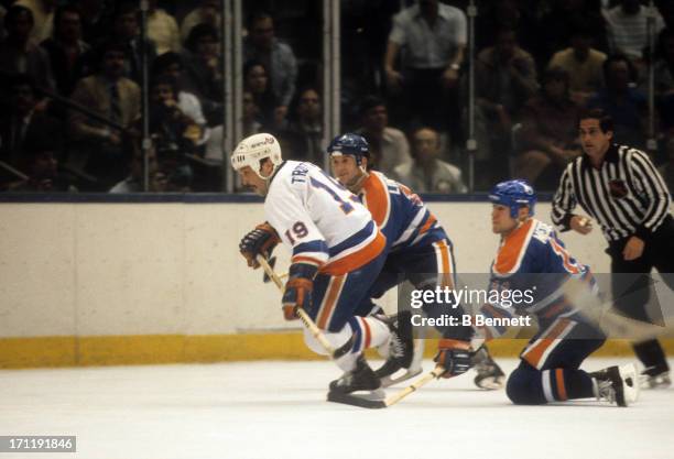Bryan Trottier of the New York Islanders skates on the ice as Mark Messier and Ken Linesman of the Edmonton Oilers follow behind during the 1984...