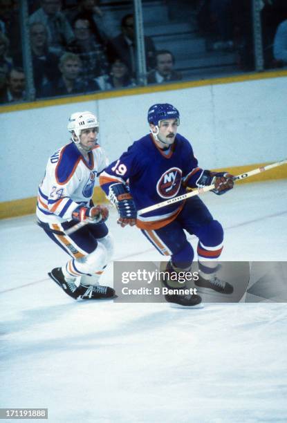 Bryan Trottier of the New York Islanders skates on the ice as Kevin McClelland of the Edmonton Oilers follows during the 1984 Stanley Cup Finals in...