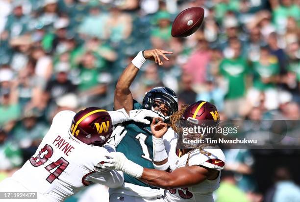 Daron Payne and Chase Young of the Washington Commanders pressure Jalen Hurts of the Philadelphia Eagles as he throws during the third quarter at...