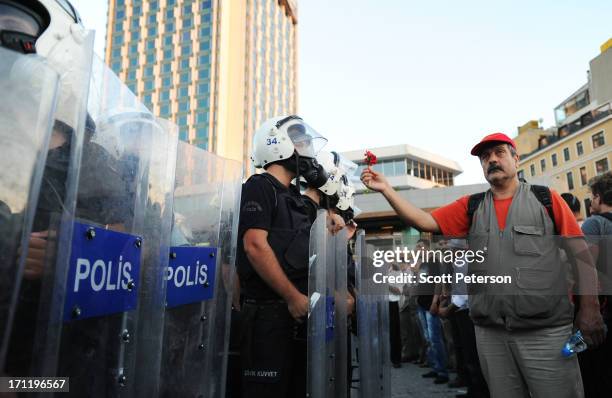 Man holds up a carnation to mark the death of four people in weeks of protests, as Turkish riot police begin moving in to clear Taksim Square, on...