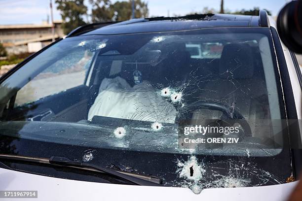 Graphic content / The body of a killed person lies covered inside a bullet-riddled car in the southern city of Sderot on October 7, 2023. At least 40...