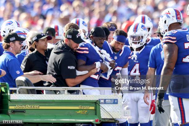 Tre'Davious White of the Buffalo Bills is helped onto a cart by medical staff and teammate Micah Hyde after being injured during the third quarter...