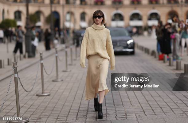 Fashion Week Guest was seen wearing black heels, a beige longsleeve with turtle-neck as well as a matching light beige skirt and dark shades before...