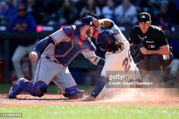 Eugenio Suarez of the Seattle Mariners slides to score at home plate past Jonah Heim of the Texas Rangers during the fourth inning at T-Mobile Park...