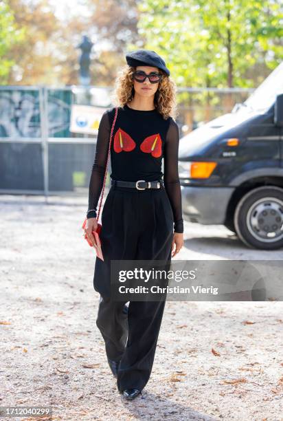 Guest wears black beret, black transparent top, wide leg pants outside Akris during the Womenswear Spring/Summer 2024 as part of Paris Fashion Week...