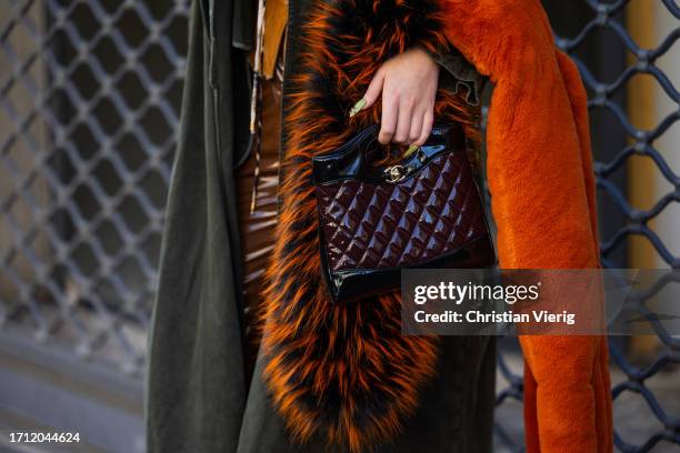 Jordan Grant wears khaki coat, Chanel bag, brown vinyl pants, heels, orange scarf outside Ottolinger during the Womenswear Spring/Summer 2024 as part...