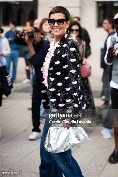 Cristina Cordula wears a pink ruffled shirt, black sequins blazer with pink details, blue jeans and silver bag, outside Giambattista Valli, during...