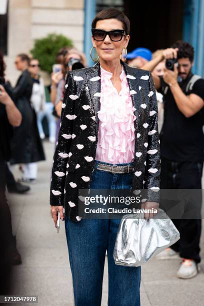 Cristina Cordula wears a pink ruffled shirt, black sequins blazer with pink details, blue jeans and silver bag, outside Giambattista Valli, during...