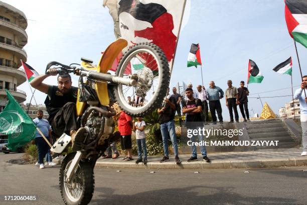 Man rides his motorcycle as people wave the Palestinian flag in Lebanon's southern city of Sidon on October 7 after Hamas militants launched a deadly...