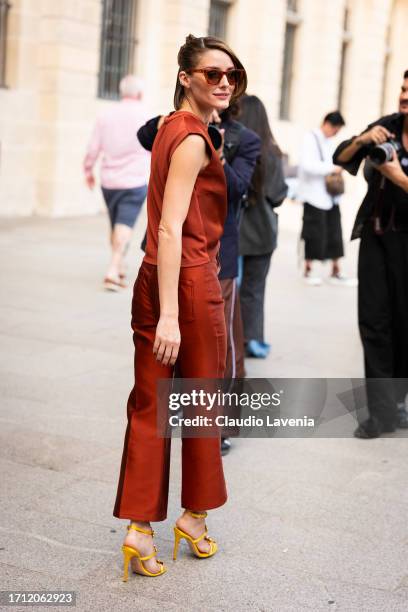 Olivia Palermo wears a rust brown top with matching pants, cream decorated clutch, yellow sandals and brown sunglasses, outside Giambattista Valli,...