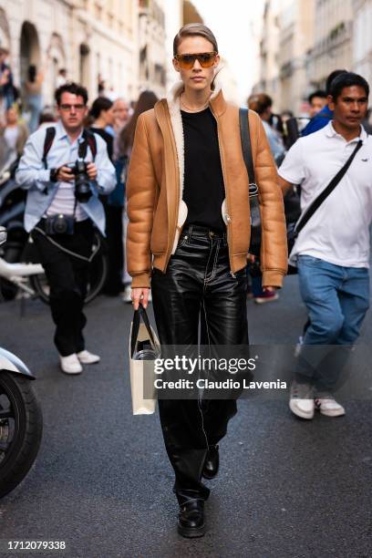 Guest wears a brown leather jacket with fur details and black leather pants, outside Victoria Beckham, during the Womenswear Spring/Summer 2024 as...