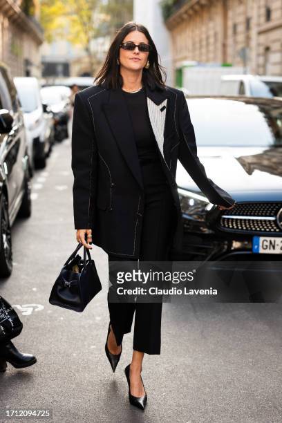 Guest wears a black blazer, black pants, black heels and bag, outside Victoria Beckham, during the Womenswear Spring/Summer 2024 as part of Paris...