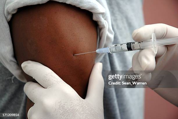 a man receiving a vaccine shot - arm needle stockfoto's en -beelden
