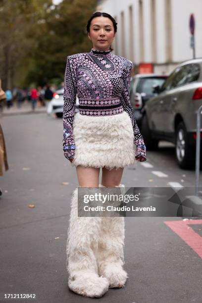 Joey Wong aka JW wears a pink and black printed long sleeves top cream fur mini skirt and cream fur boots, outside Leonard Paris, during the...