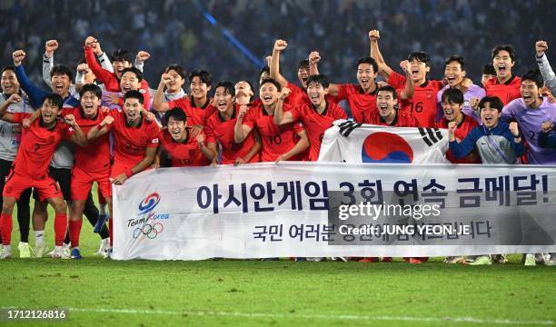 South Korea's players celebrate their victory with a banner reading "Third consecutive Asian Games gold medals!" after the men's football gold medal...