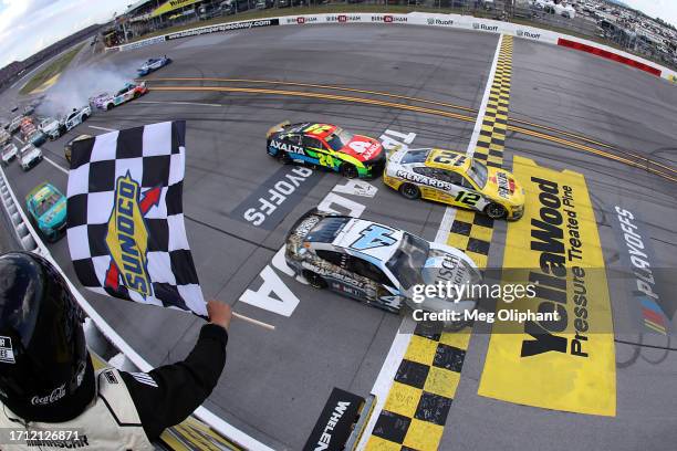 Ryan Blaney, driver of the Menards/Pennzoil Ford, takes the crosses the finish line ahead of Kevin Harvick, driver of the Busch Light Camo Ford, to...