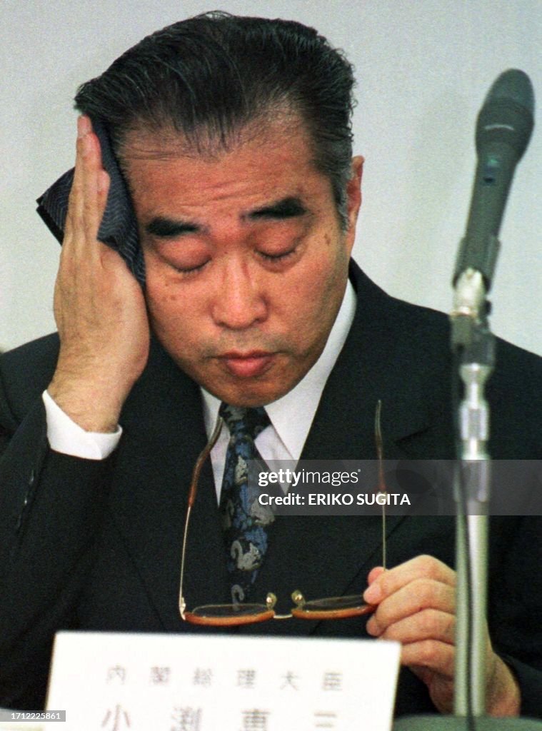 Japan's Prime Minister Keizo Obuchi uses a handkerchief to wipe off ...