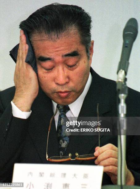 Japan's Prime Minister Keizo Obuchi uses a handkerchief to wipe off perspiration as he meets with small and medium-sized business proprietors and...