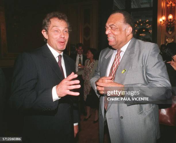 British Prime Minister Tony Blair laughs 18 June with Jamaican High Commissioner Derrick Heaven at a Foreign and Commonwealth office reception, for...