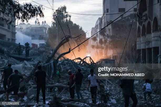 Graphic content / People walk atop the rubble of a tower destroyed in an Israeli air stike in Gaza City on October 7, 2023. Palestinian militants...