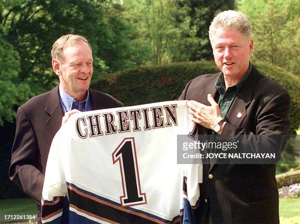 President Bill Clinton presents Canadian Prime Minister Jean Chretien with a Washington Capital hockey team jersey after winning a bet against the...