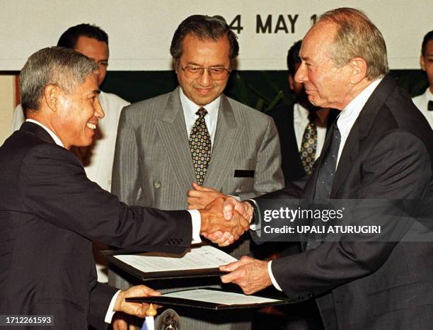 Malaysian Prime Minister Mahathir Mohamad witnesses the exchange of documents by the Chairman of the Software International Corporation of Malaysia,...