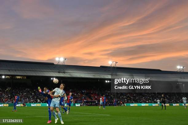 Crystal Palace's English defender Nathaniel Clyne and Nottingham Forest's New Zealand striker Chris Wood compete for the ball as the sun sets behind...