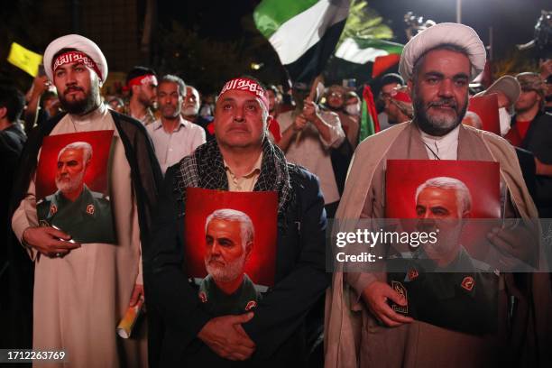 Iranians carry pictures of slain Revolutionary Guards commander Qasem Soleimani as they attend a gathering in Tehran on October 7 to express their...