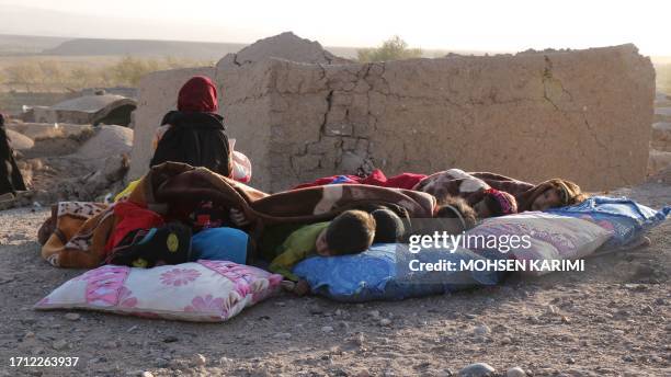 Afghan children rest under a blanket beside damaged houses after earthquake in Sarbuland village of Zendeh Jan district of Herat province on October...
