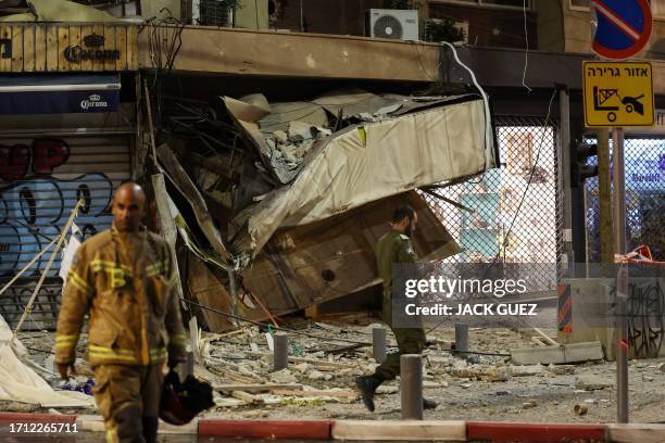 Rescuer walks in front of a damaged shop in Tel Aviv, after it was hit by a rocket fired by Palestinian militants from the Gaza Strip on October 7,...