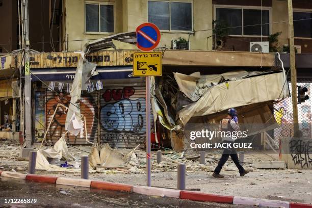 An Israeli rescuer walks in front of a damaged shop in Tel Aviv, after it was hit by a rocket fired by Palestinian militants from the Gaza Strip on...