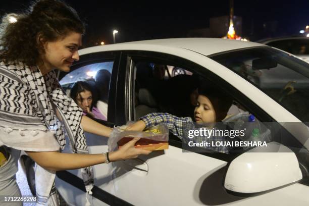 Woman passes out sweets to passers by in Damascus on October 7 to express their solidarity with Palestine after Hamas militants launched a deadly...