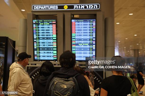 Passengers look at a departure board at Ben Gurion Airport near Tel Aviv, Israel, on October 7 as flights are canceled because of the Hamas surprise...