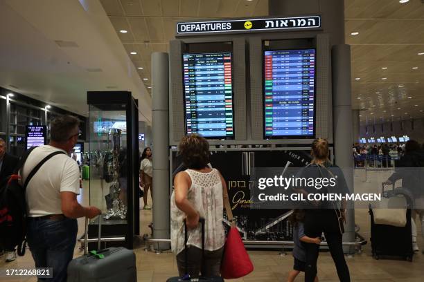 Passengers look at a departure board at Ben Gurion Airport near Tel Aviv, Israel, on October 7 as flights are canceled because of the Hamas surprise...