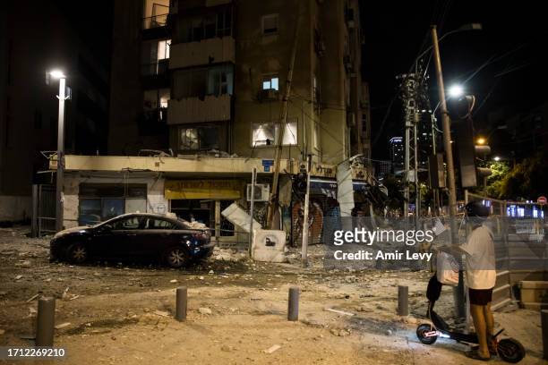 Man passes the scene where a rocket fired from Gaza strip hit a building on October 7, 2023 in Tel Aviv, Israel. Israel's Defense Forces say that...