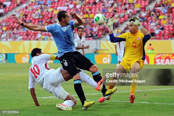 Matias Aguirregaray of Uruguay collides with Nicolas Vallar of Tahiti and Gilbert Meriel of Tahiti tends goal during the FIFA Confederations Cup...