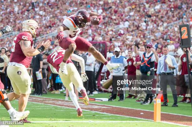Running back Bhayshul Tuten of the Virginia Tech Hokies leaps over defensive back Fentrell Cypress II of the Florida State Seminoles for a touchdown...