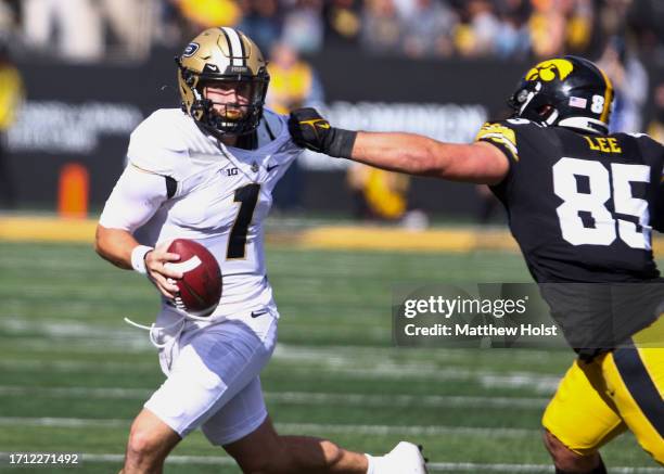 Quarterback Hudson Card of the Purdue Boilermakers scrambles during the first half away from defensive lineman Logan Lee of the Iowa Hawkeyes at...